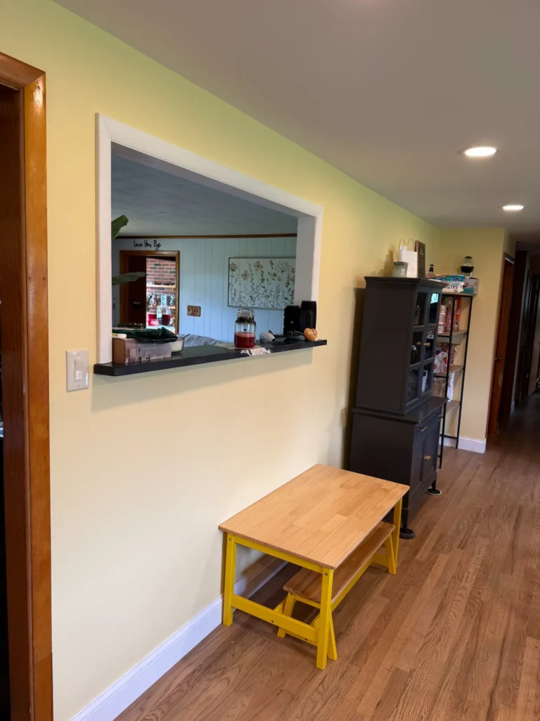 Updated room with light yellow walls, a pass-through opening to the kitchen and wood-look flooring